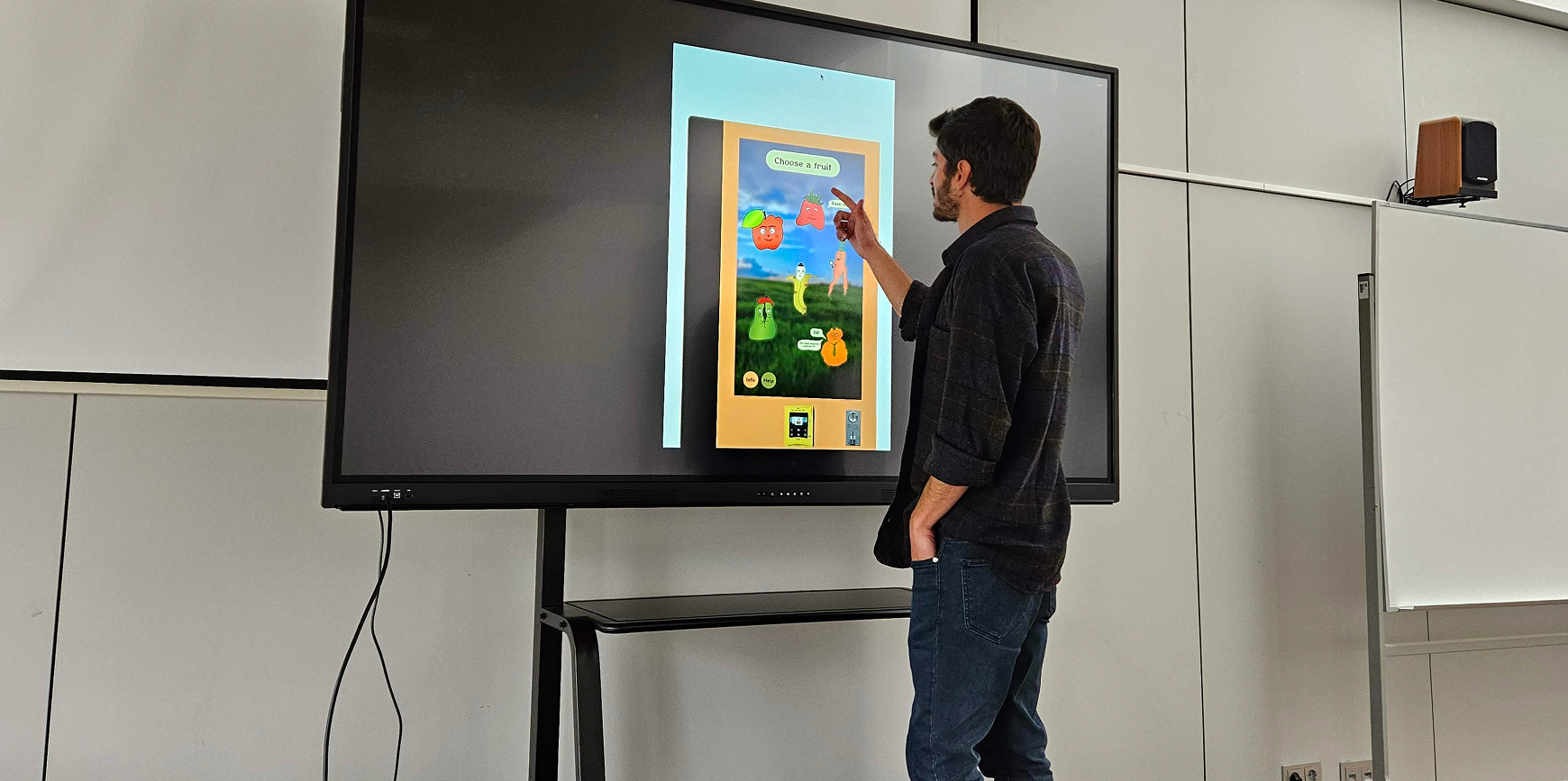 User standing in front of a TV showing the machine prototype